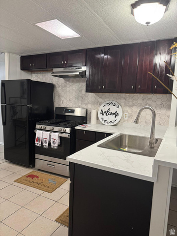 8155 South Redwood Road, Unit 95 West Jordan, UT 84088 - Photo 1 of 1 Kitchen with backsplash, stainless steel gas range oven, light tile patterned floors, freestanding refrigerator, and under cabinet range hood