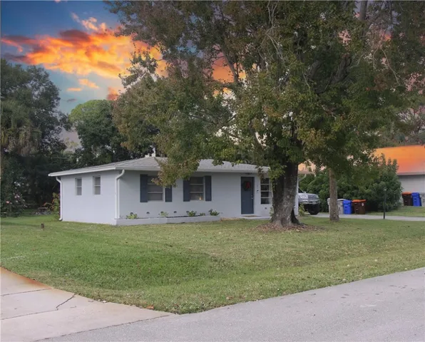 a front view of house with yard and trees all around