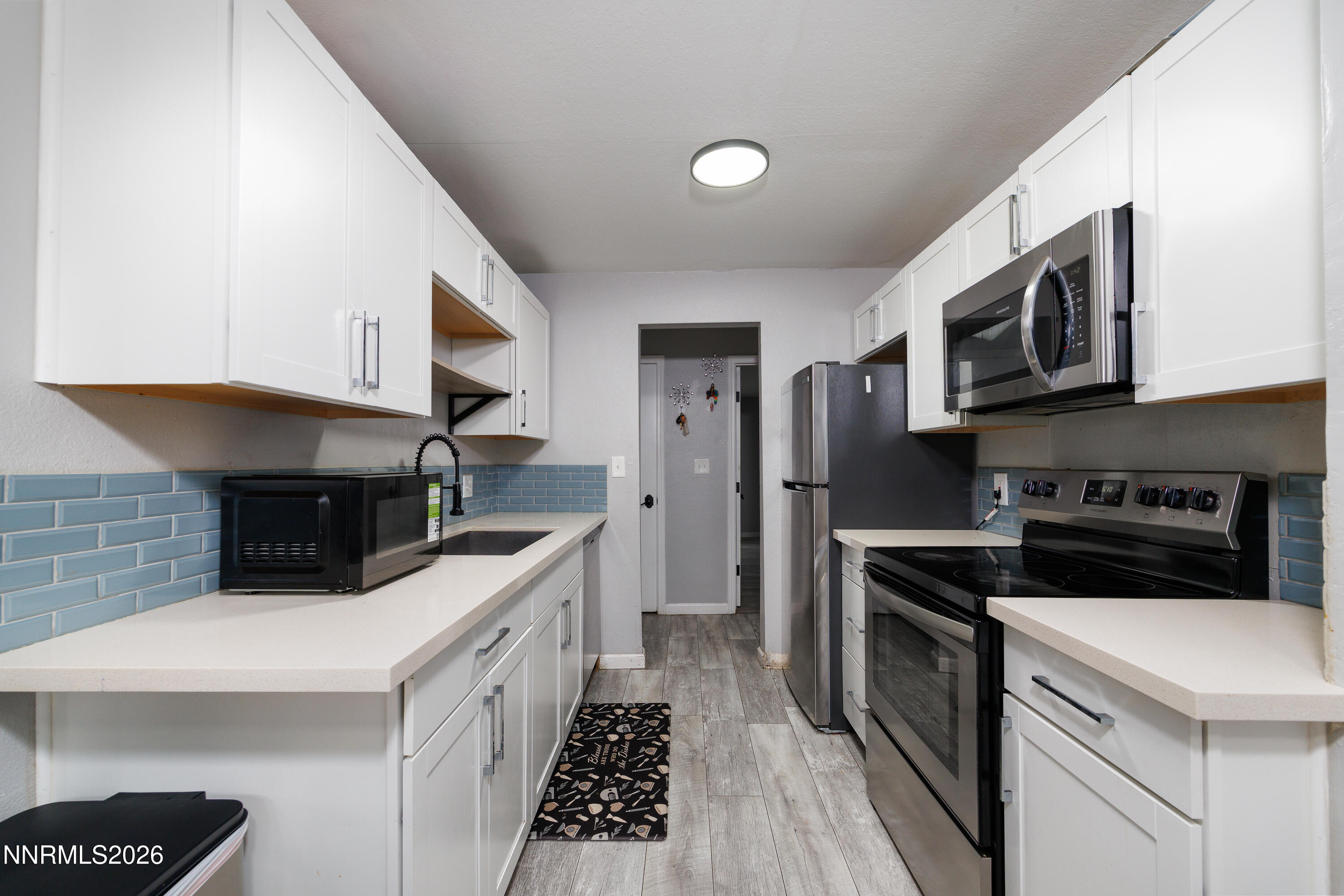 3935 Clear Acre Lane, Unit 214 Reno, NV 89512 - Photo 11 of 15 a kitchen with stainless steel appliances a stove a microwave a sink and cabinets