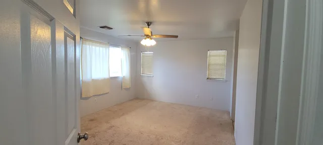 en empty room with windows and ceiling fan