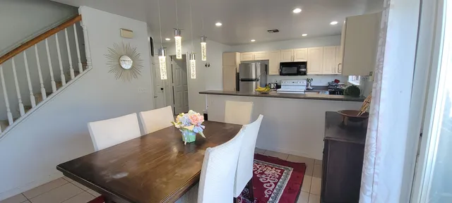 a kitchen with stainless steel appliances granite countertop sink refrigerator dining table and chairs