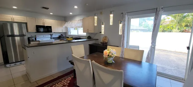 a kitchen with stainless steel appliances granite countertop a refrigerator a sink dishwasher a stove a dining table and chairs with wooden floor