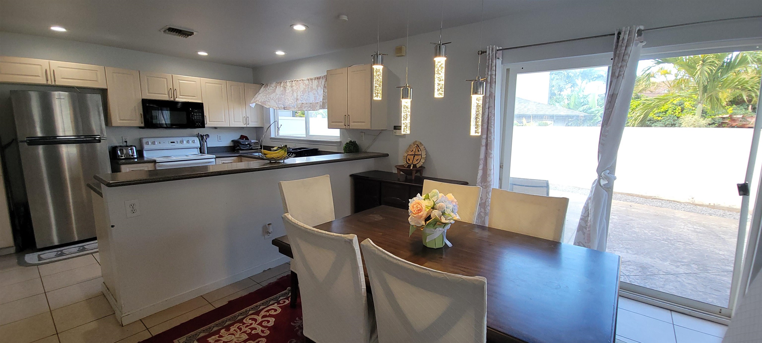 10 West Makahehi Loop Kahului, HI 96732 - Photo 7 of 18 a kitchen with stainless steel appliances granite countertop a refrigerator a sink dishwasher a stove a dining table and chairs with wooden floor
