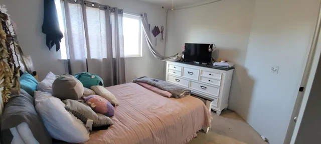 a bedroom with a bed a flat screen tv and window