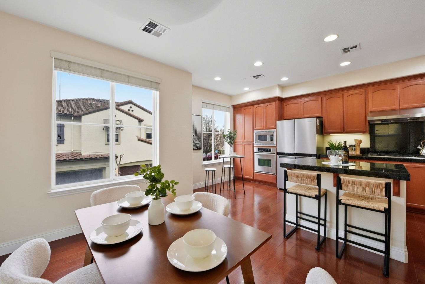 48962 Woodgrove Common Fremont, CA 94539 - Photo 4 of 36 a kitchen with stainless steel appliances kitchen island granite countertop wooden floor dining table and chairs