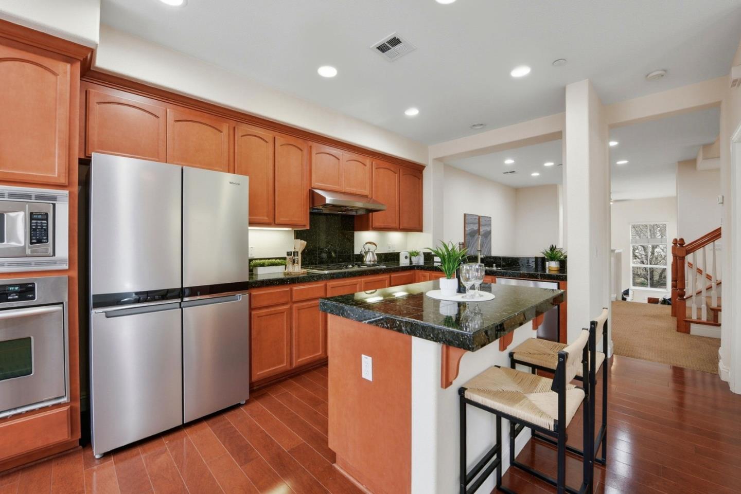 48962 Woodgrove Common Fremont, CA 94539 - Photo 7 of 36 a kitchen with stainless steel appliances granite countertop a refrigerator a stove a sink a dining table and chairs with wooden floor