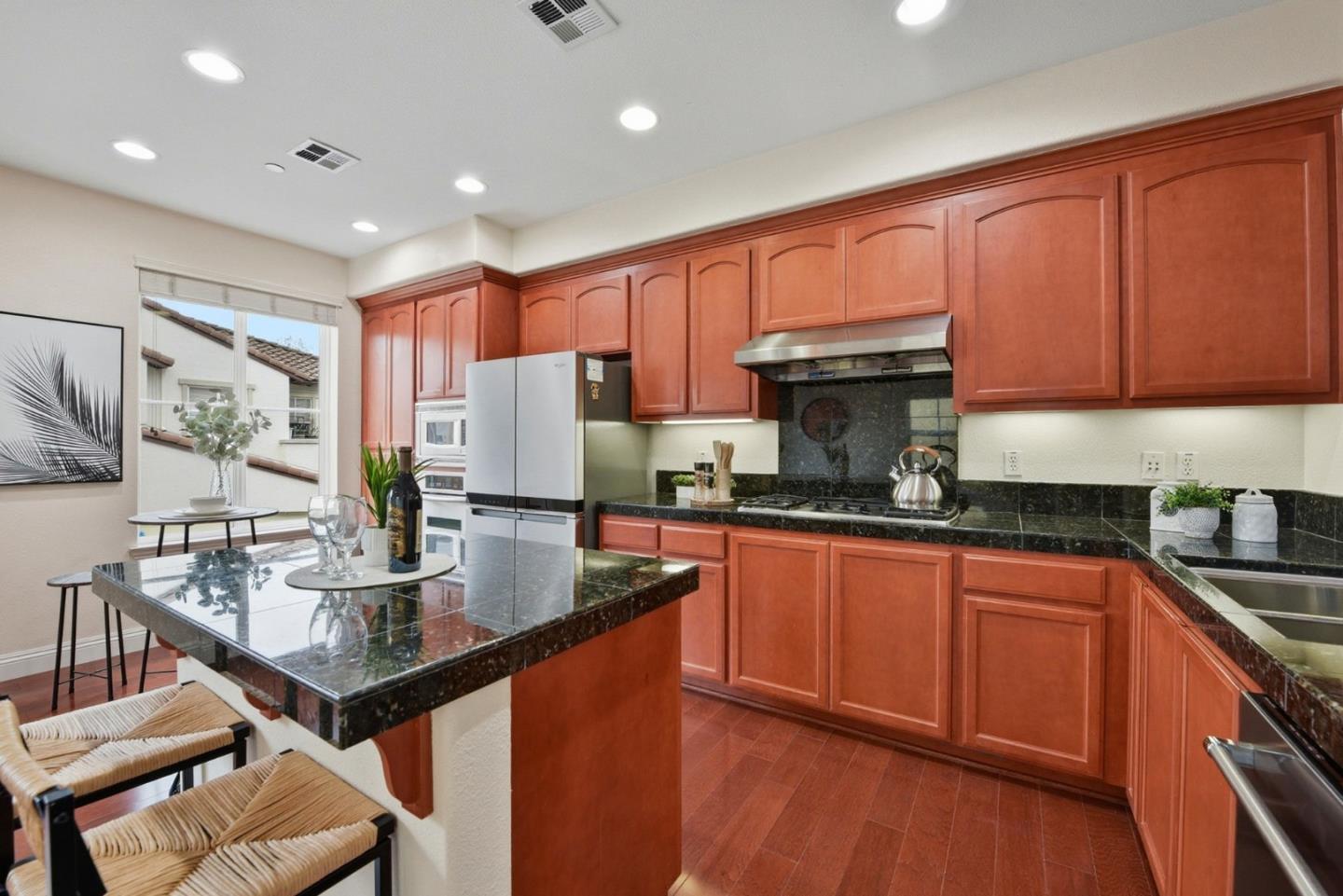 48962 Woodgrove Common Fremont, CA 94539 - Photo 10 of 36 a kitchen with stainless steel appliances granite countertop a stove a sink dishwasher and a refrigerator with wooden cabinets