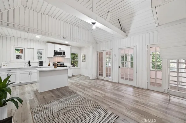 a large white kitchen with wooden floor and outdoor space
