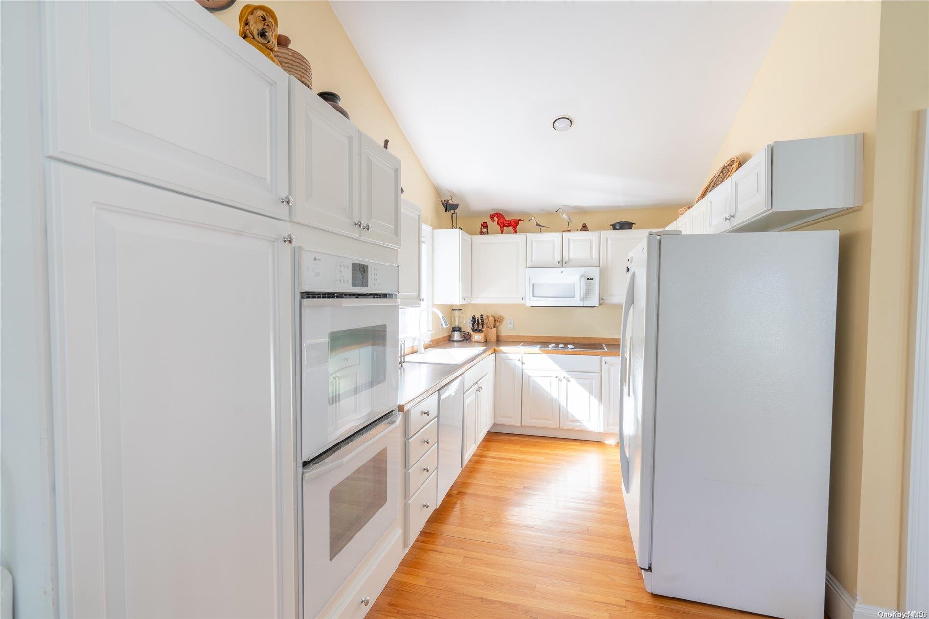 231 5th Avenue Greenport, NY 11944 - Photo 10 of 18 a kitchen with white cabinets and refrigerator
