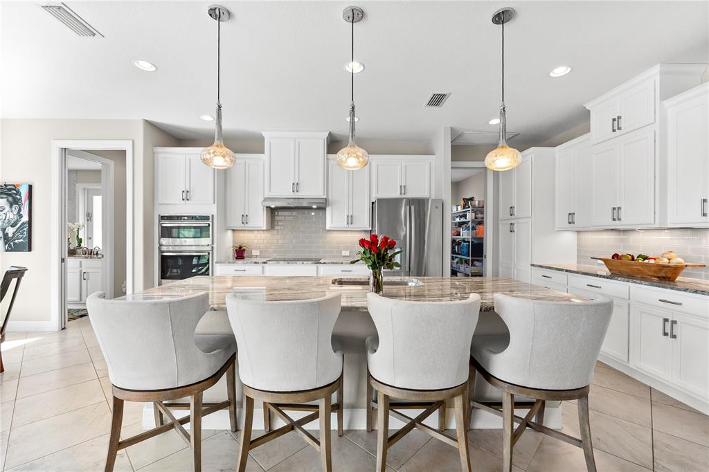 10491 Sarasota Road Port Charlotte, FL 33981 - Photo 11 of 44 a kitchen with kitchen island a dining table chairs and white cabinets