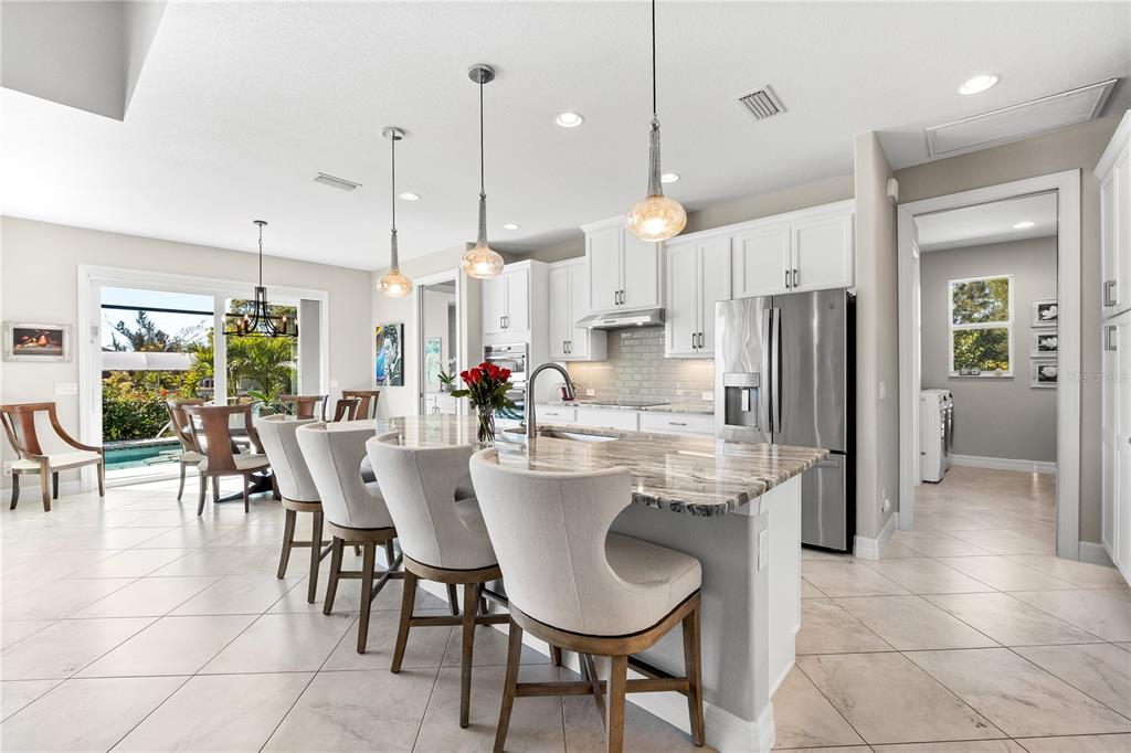 10491 Sarasota Road Port Charlotte, FL 33981 - Photo 12 of 44 a kitchen with stainless steel appliances kitchen island granite countertop a dining table chairs and sink
