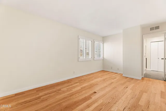 a view of empty room with wooden floor and fan