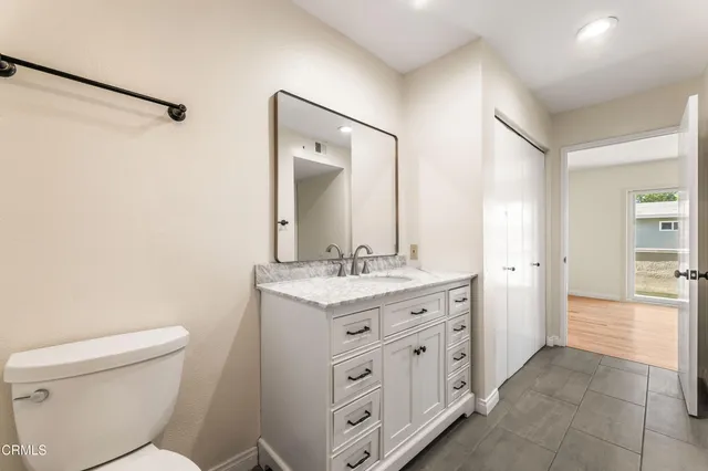 a bathroom with a granite countertop sink a toilet and a mirror