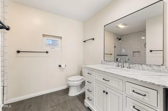 a bathroom with a granite countertop sink mirror vanity and toilet