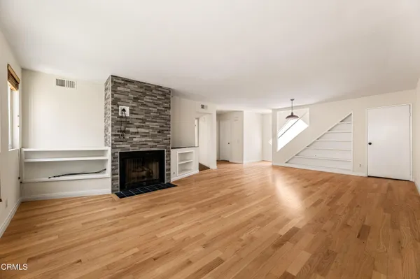 an empty room with wooden floor fireplace and windows