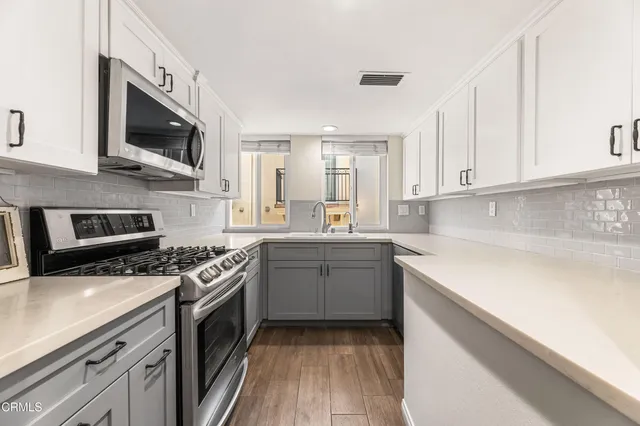 a kitchen with a sink a stove top oven and cabinets