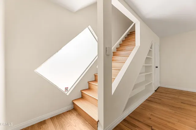 a view of staircase with wooden floor and white walls