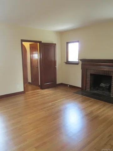 a view of empty room with wooden floor and fireplace
