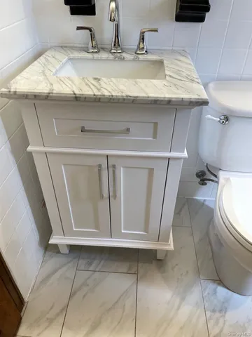 a bathroom with a granite countertop sink and a toilet