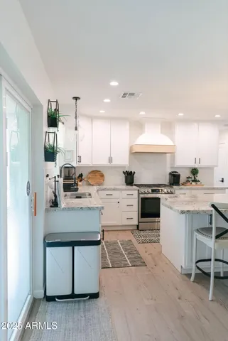 a kitchen with stainless steel appliances white cabinets a sink a stove a refrigerator and a oven