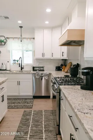 a kitchen with stainless steel appliances granite countertop a stove a sink dishwasher and a refrigerator