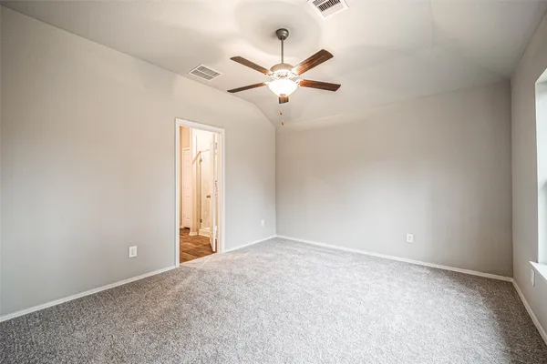 an empty room with chandelier fan and windows