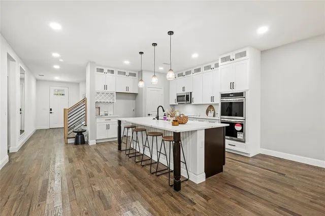 a kitchen that has a lot of cabinets a sink and wooden floor