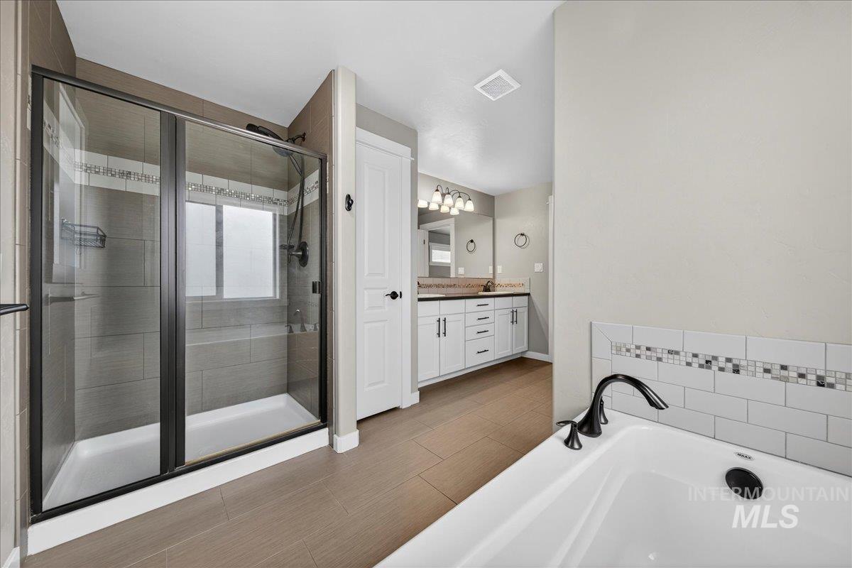 12200 West Oneida Street Boise, ID 83709 - Photo 11 of 35 Full bathroom featuring vanity, a tub, and a shower stall