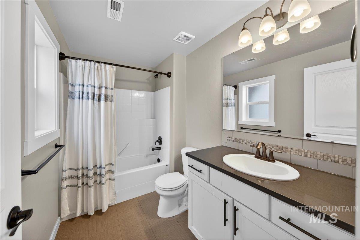12200 West Oneida Street Boise, ID 83709 - Photo 15 of 35 Bathroom featuring vanity, backsplash, and shower / bath combo with shower curtain