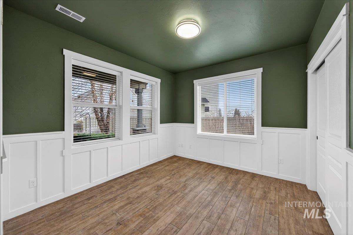 12200 West Oneida Street Boise, ID 83709 - Photo 24 of 35 Spare room featuring healthy amount of natural light, wainscoting, wood finished floors, and a decorative wall