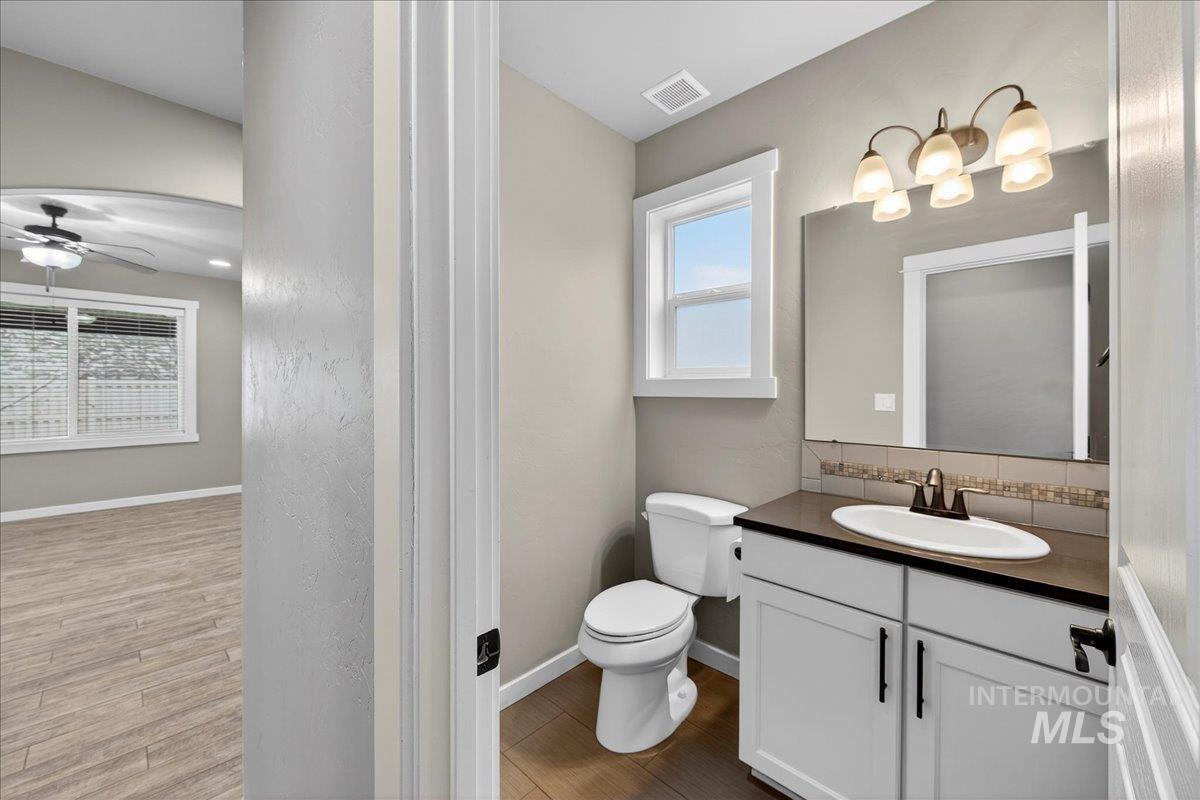 12200 West Oneida Street Boise, ID 83709 - Photo 27 of 35 Bathroom featuring vanity, dark wood-type flooring, backsplash, and ceiling fan