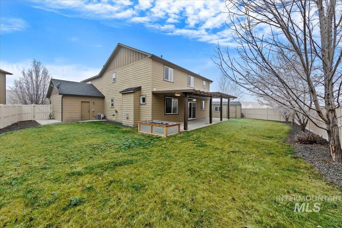 12200 West Oneida Street Boise, ID 83709 - Photo 32 of 35 Rear view of house with a fenced backyard, board and batten siding, and a patio area
