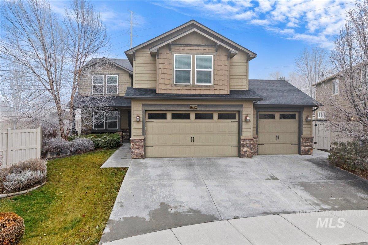 12200 West Oneida Street Boise, ID 83709 - Photo 34 of 35 Craftsman-style home with stone siding, driveway, roof with shingles, and an attached garage