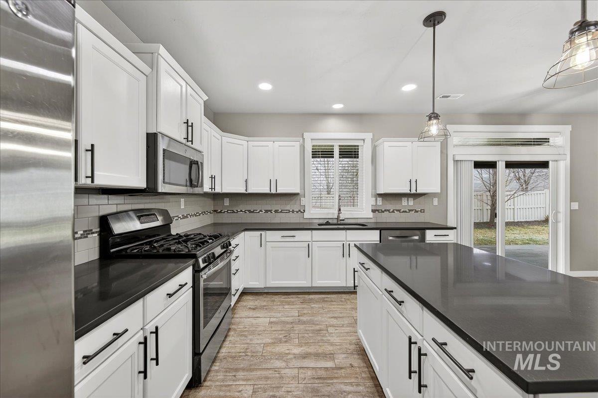 12200 West Oneida Street Boise, ID 83709 - Photo 5 of 35 Kitchen featuring appliances with stainless steel finishes, recessed lighting, pendant lighting, white cabinetry, and tasteful backsplash