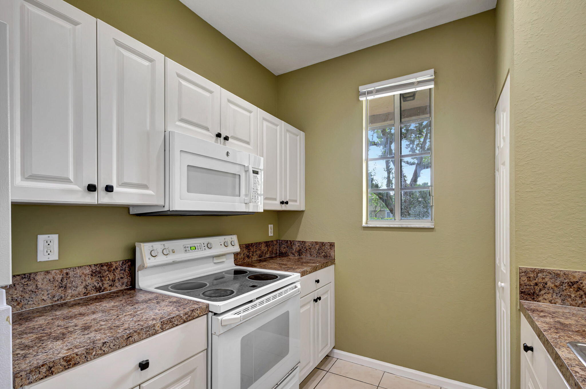 2025 Island Drive Riviera Beach, FL 33404 - Photo 15 of 46 a kitchen with granite countertop white cabinets and white appliances