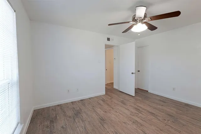 an empty room with wooden floor fan and window