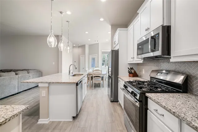 a kitchen with stainless steel appliances granite countertop a stove oven and a white cabinets