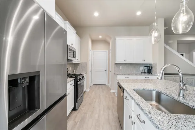 a kitchen with a sink dishwasher a refrigerator and a stove with wooden floor