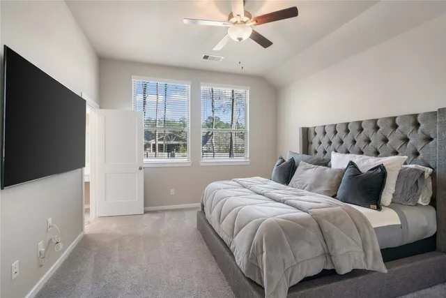 a bedroom with a large bed and a flat tv screen on dresser