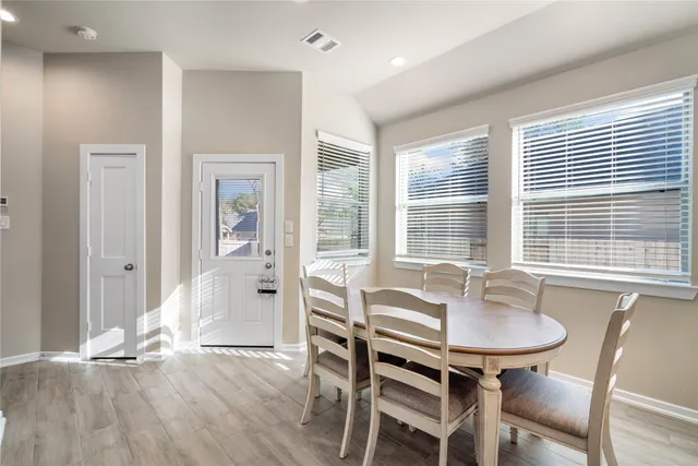 a dining room with wooden floor and large windows