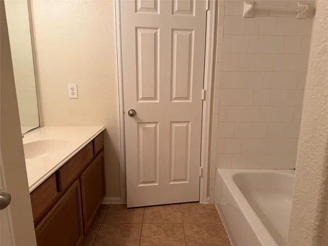 a bathroom with a tub sink vanity and mirror