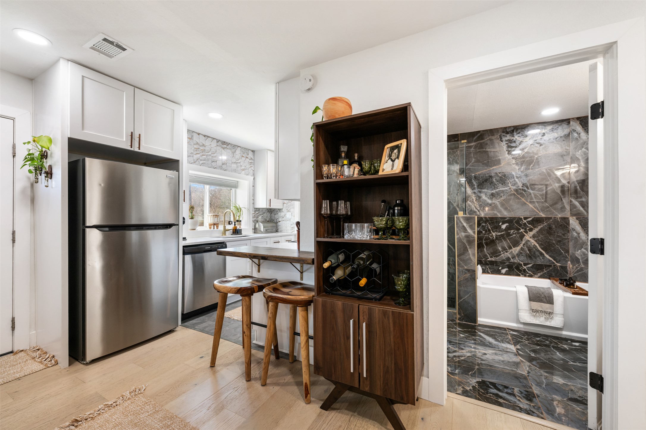 1616 Webberville Road, Unit A Austin, TX 78721 - Photo 6 of 28 Kitchen with appliances with stainless steel finishes, white cabinetry, open shelves, a kitchen bar, and light wood-style flooring