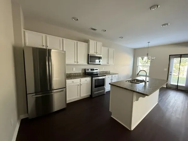 a kitchen with granite countertop a refrigerator stove and sink