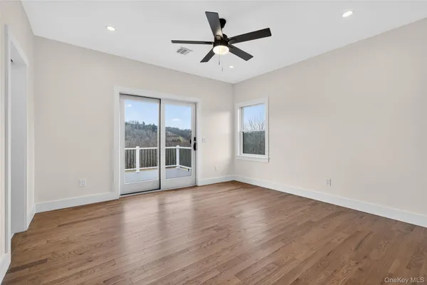 a view of empty room with wooden floor and fan