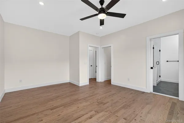 an empty room with wooden floor and ceiling fan