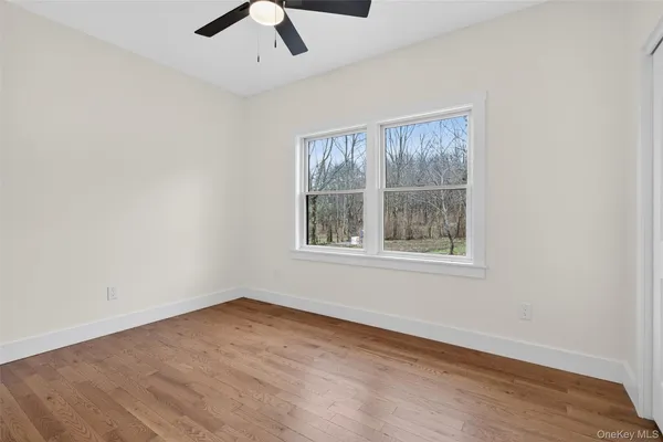 an empty room with a window and a ceiling fan