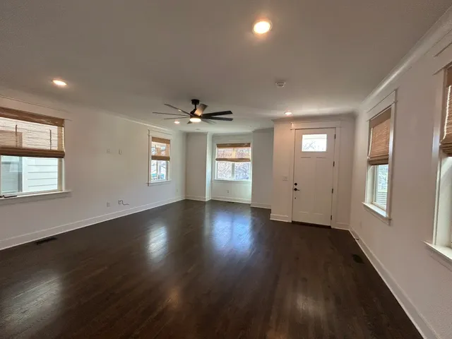 an empty room with wooden floor fan and windows