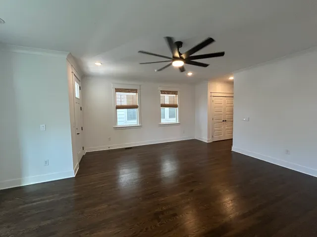 an empty room with wooden floor fan and windows