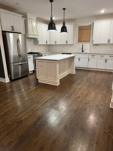 a living room with stainless steel appliances granite countertop furniture wooden floor and a kitchen view