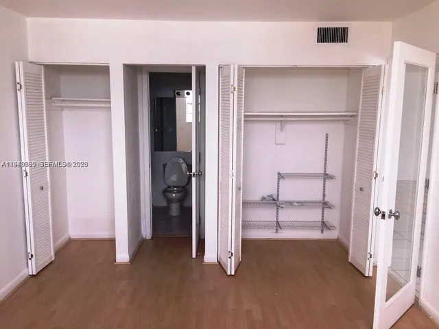 a view of an empty room with closet and a window